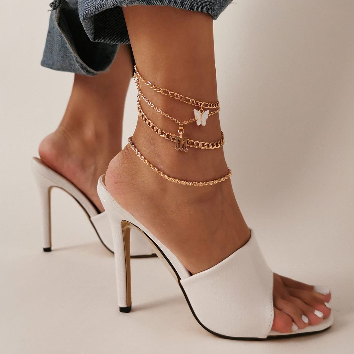 a woman wearing a butterfly multilayer gold anklet 