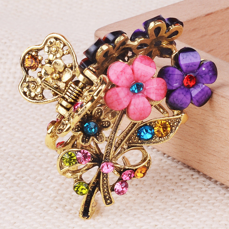 Decorative hair clip with flowers and gold accents on a neutral background