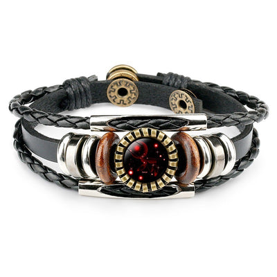 A black leather bracelet with woven and smooth straps features a central circular emblem depicting a red zodiac design, flanked by wood and silver beads.