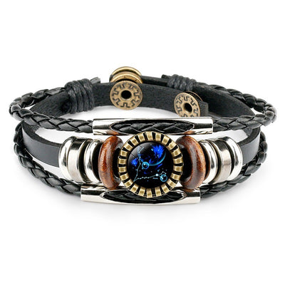 A stylish black leather bracelet with braided straps, featuring metal and wooden beads. The centerpiece is a round, artful design displaying a vivid blue pattern.