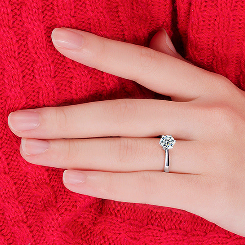 Hand wearing a diamond ring on a red textured fabric background