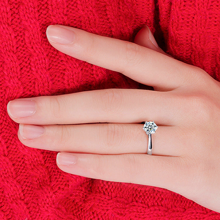 Hand wearing a diamond ring on a red textured fabric background
