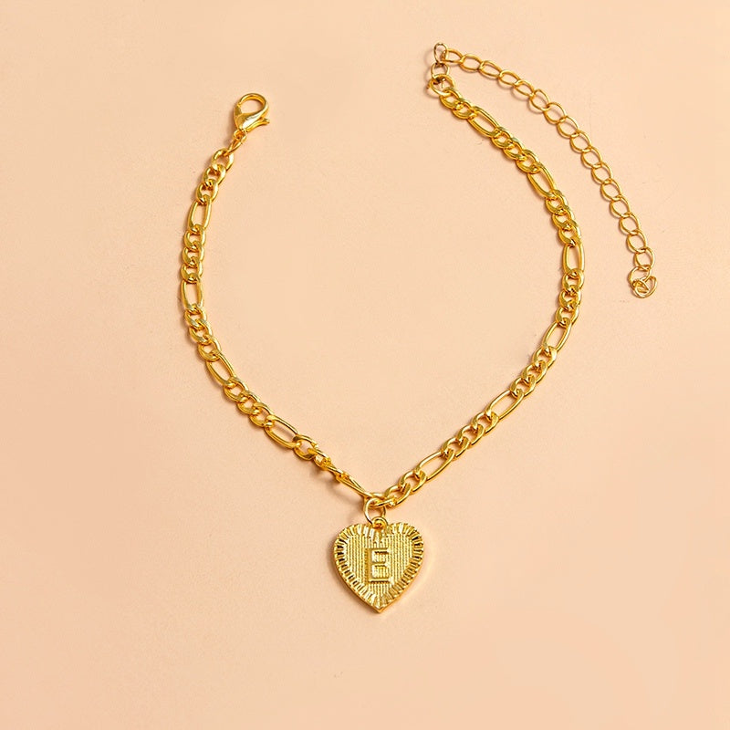 Gold chain bracelet with a heart-shaped charm letter E on a beige background
