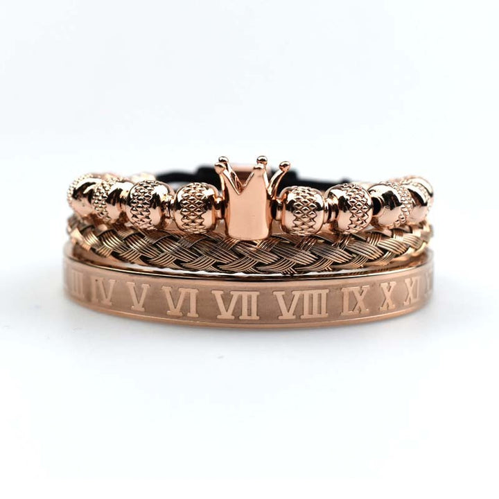 Rose gold ring with crown design and Roman numeral engraving on a white background