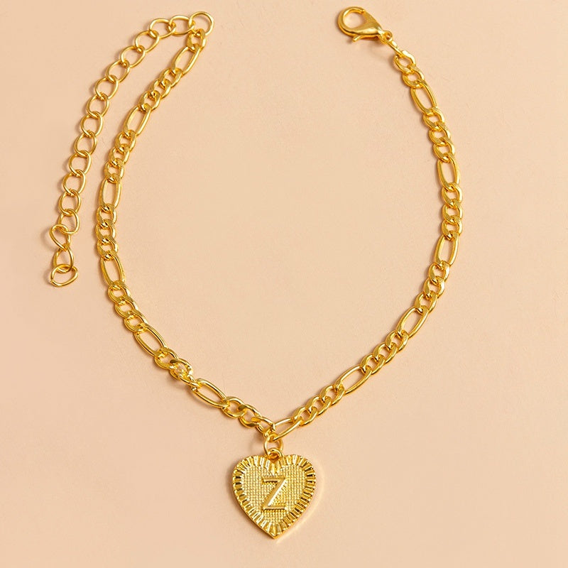 Gold chain bracelet with a heart-shaped charm letter Z on a beige background