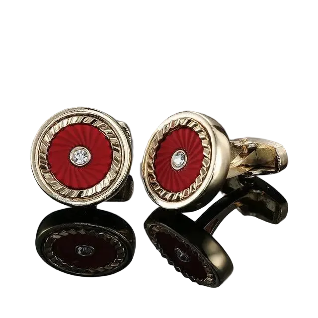 Gold cufflinks with red circular design and diamond center on a white background