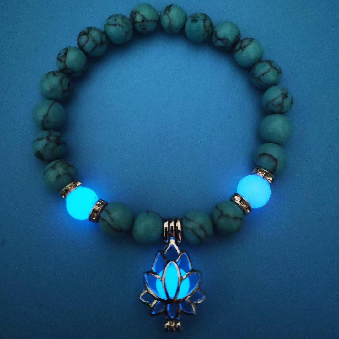 Turquoise beaded bracelet with a glowing blue lotus pendant on a blue background