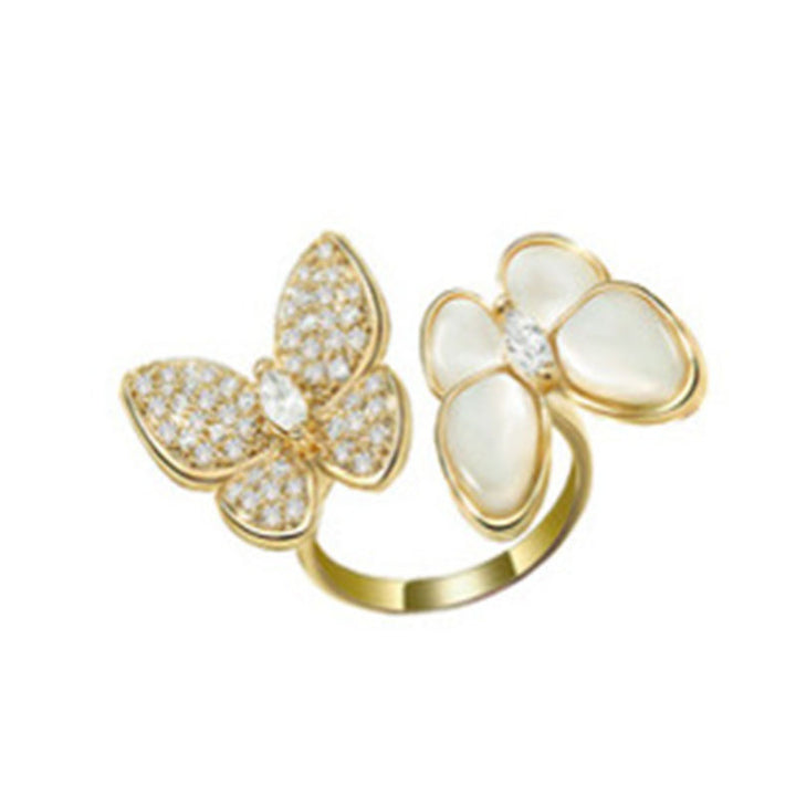 Gold butterfly-shaped rings with gemstones on a white background