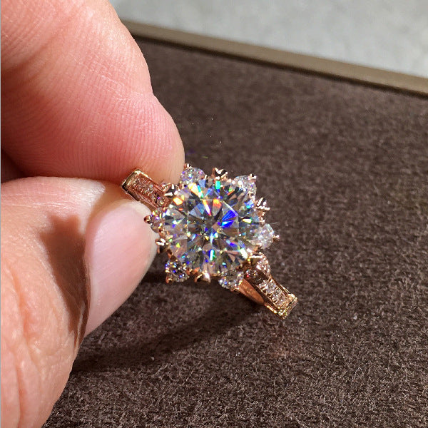 Fingers holding Ring with a colorful gemstone set against a brown background