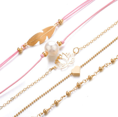 Three gold bracelets and  two pink cord bracelets one with a feather shaped charm one pearl bead on a white background