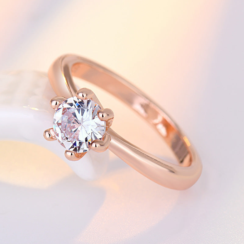 Rose gold ring with a clear gemstone on a soft gradient background