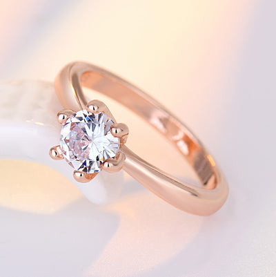 Rose gold ring with a clear gemstone on a soft gradient background