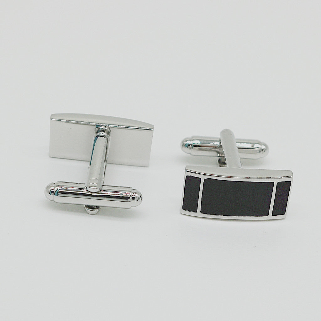 Silver cufflinks with a black rectangular accent on a light gray background