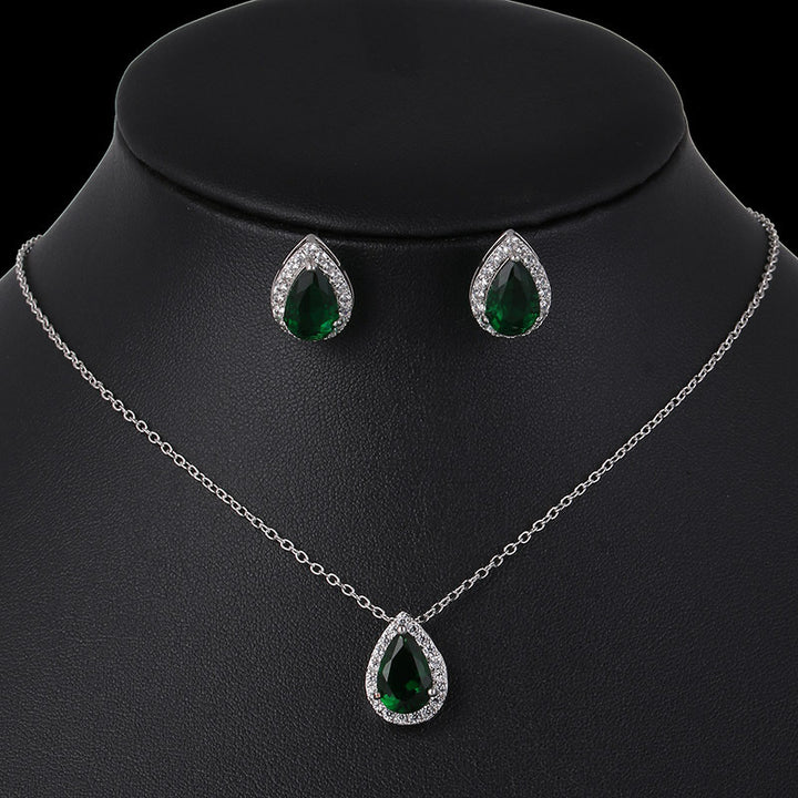 Jewelry set with necklace and earrings featuring green teardrop stones on a black mannequin.