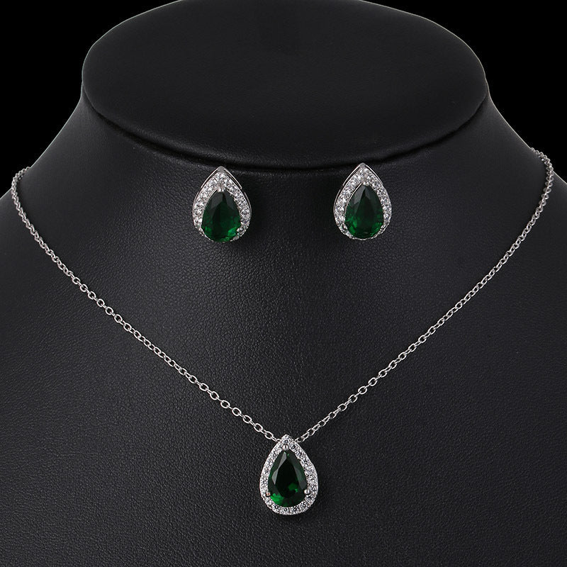Jewelry set with necklace and earrings featuring green teardrop stones on a black mannequin.