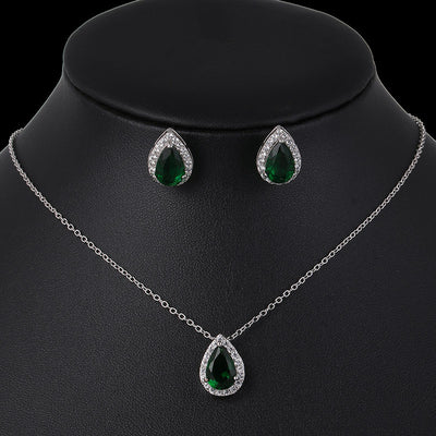Jewelry set with necklace and earrings featuring green teardrop stones on a black mannequin.