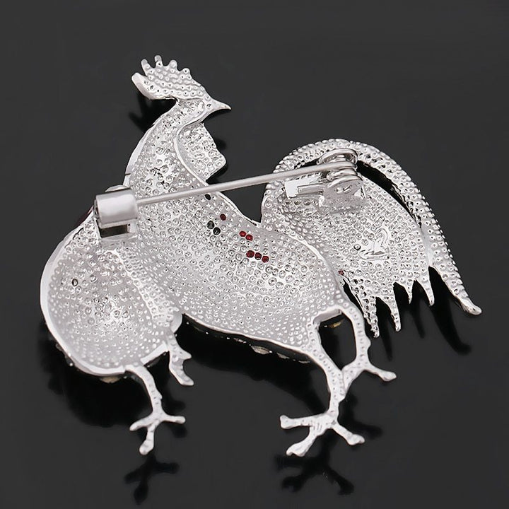 Back side view of the rooster-shaped brooch with gemstones on a black background