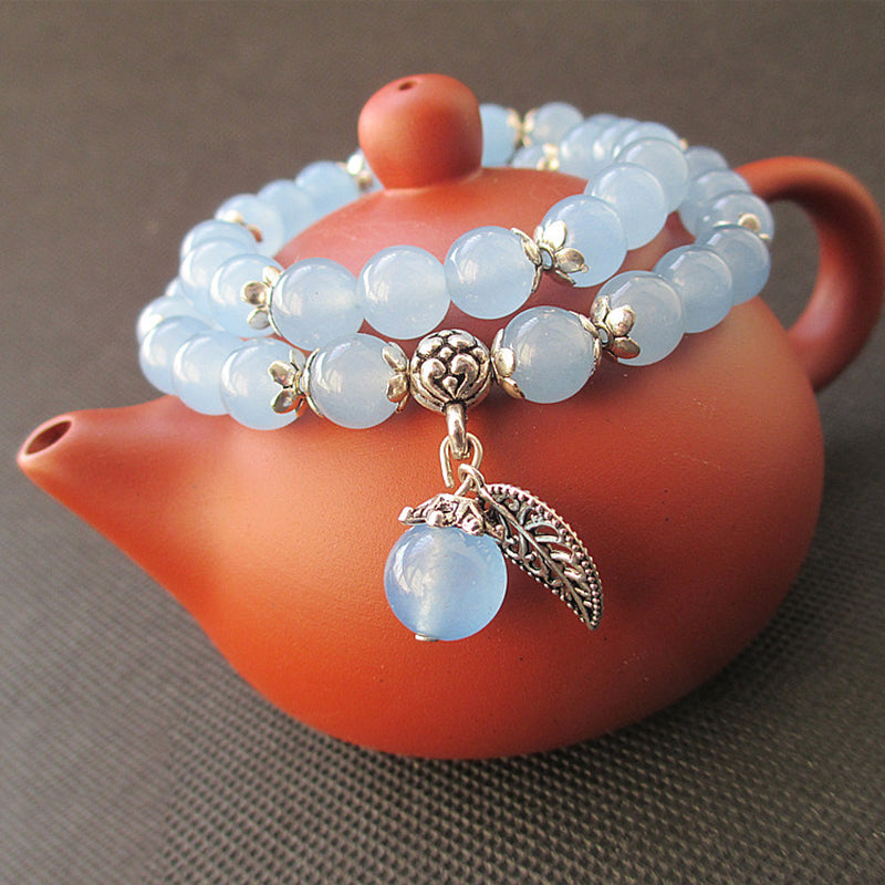 Blue beaded bracelet with a gold charm on an orange teapot