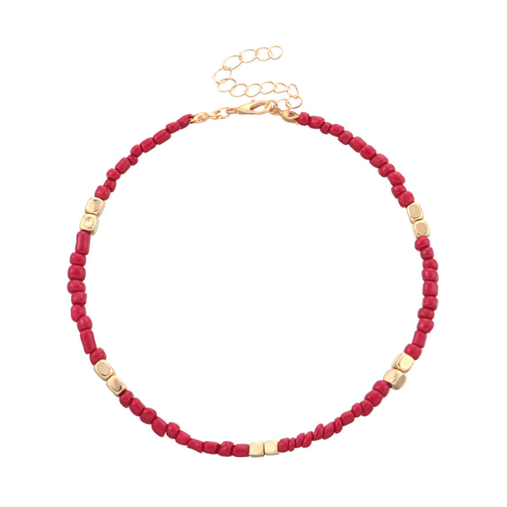 anklet with red beads and gold accents on a white background