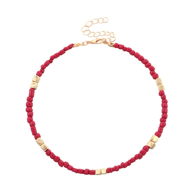 anklet with red beads and gold accents on a white background