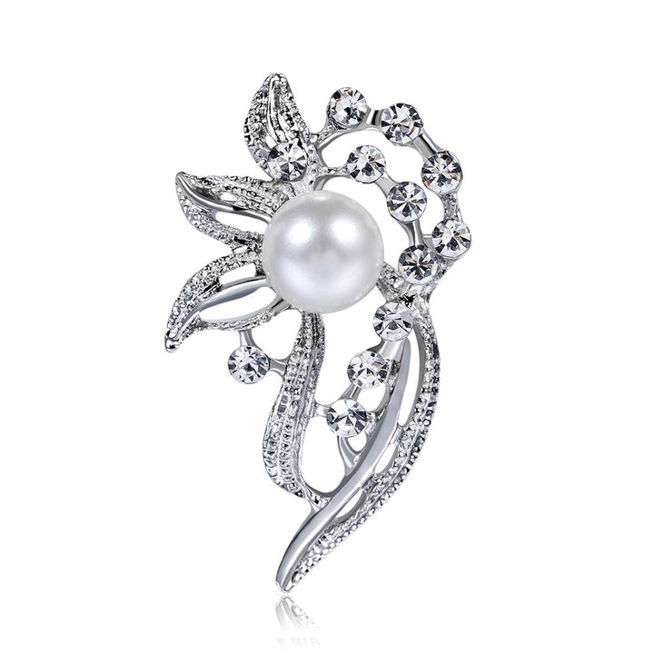 Silver brooch with a pearl and crystal accents on a white background