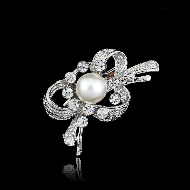 Silver brooch with a pearl and crystals on a black background