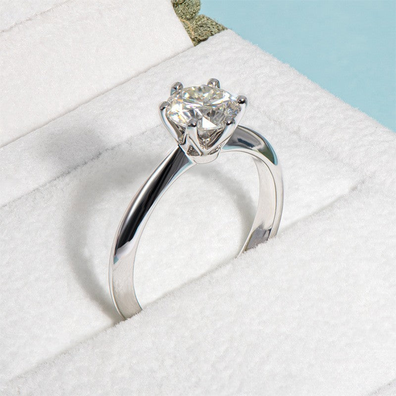 Silver ring with a diamond on a white cushion
