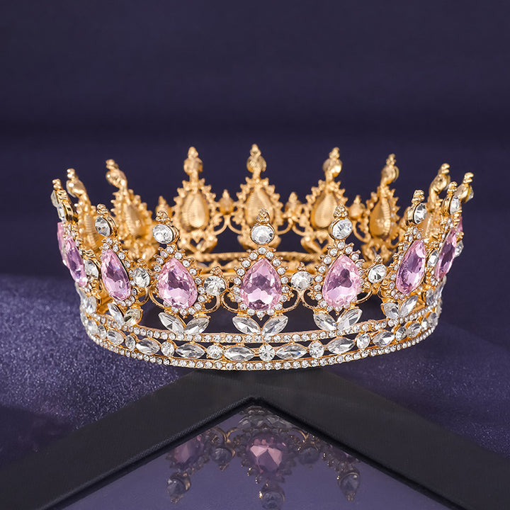 Gold and pink gemstone tiara on a reflective surface with a dark background