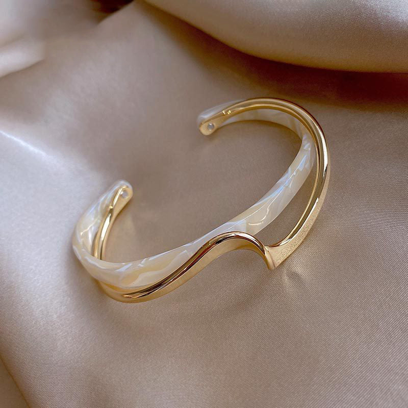 Gold and pearl bracelet on a beige fabric background
