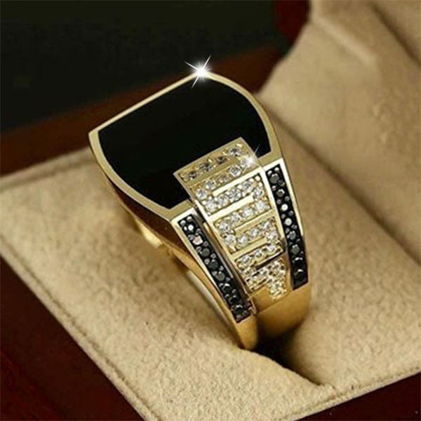 Gold ring with black and white gemstones on a beige cushion