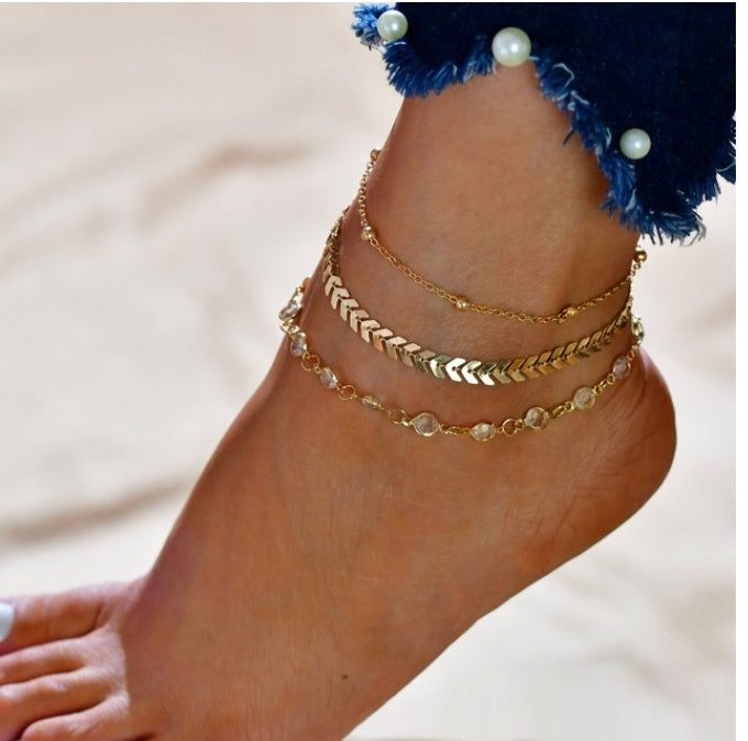 Gold anklets on a foot with a blurred background
