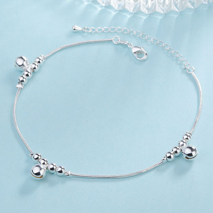 Silver anklet with beads on a light blue background