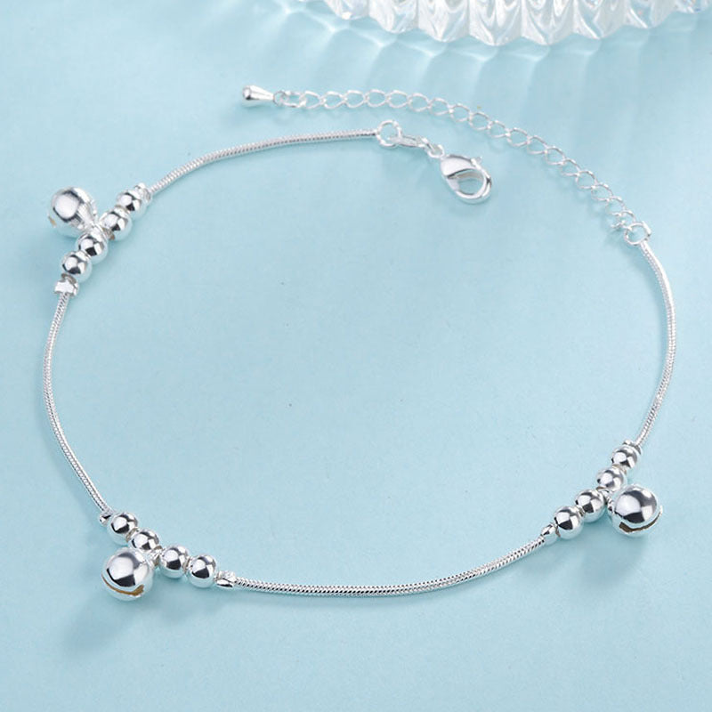 Silver anklet with beads on a light blue background