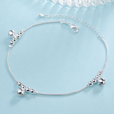 Silver anklet with beads on a light blue background