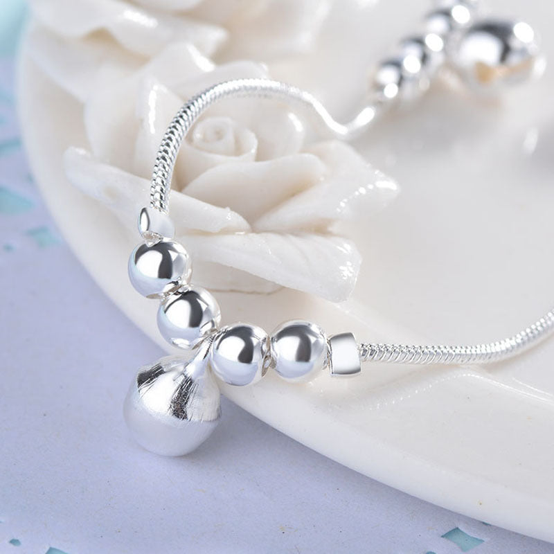 close up of Silver beaded bracelet on a white shell background