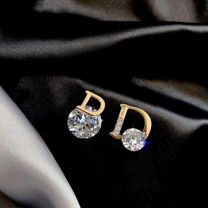 Gold earrings with clear gemstones on a black fabric background