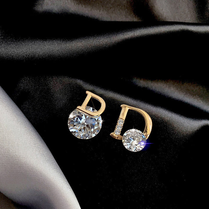 Gold earrings with clear gemstones on a black fabric background