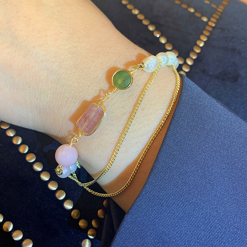 Gold bracelet with colorful beads on a wrist against a blue fabric background