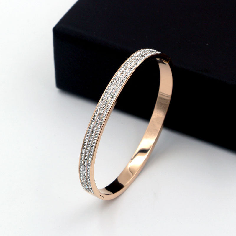 Rose gold bracelet with clear stones on a white surface