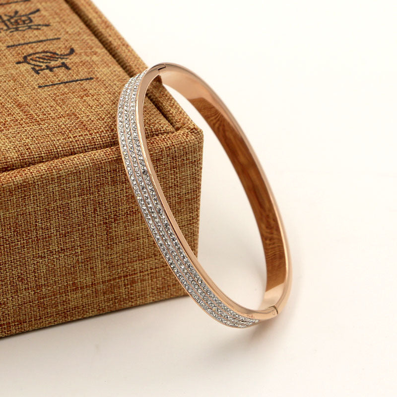 Rose gold bracelet with diamond accents on a textured brown box