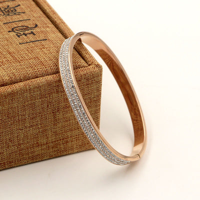 Rose gold bracelet with diamond accents on a textured brown box