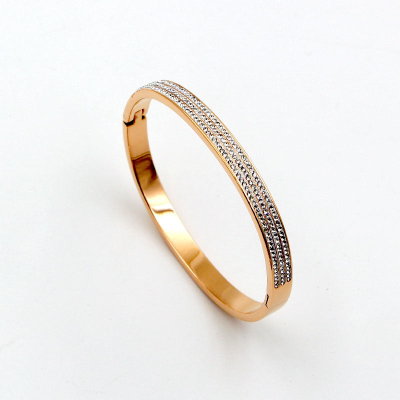 Gold bracelet with diamond accents on a light gray background