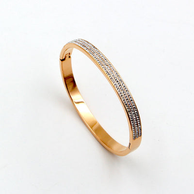 Gold bracelet with diamond accents on a light gray background