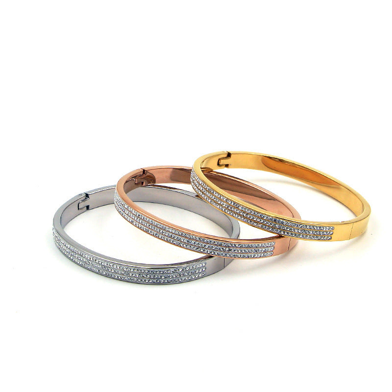 Three stacked bracelets in gold, rose gold, and silver on a white background