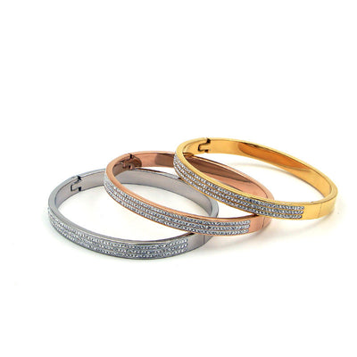 Three stacked bracelets in gold, rose gold, and silver on a white background