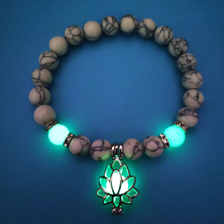 Bracelet with glowing green lotus charm on a blue background