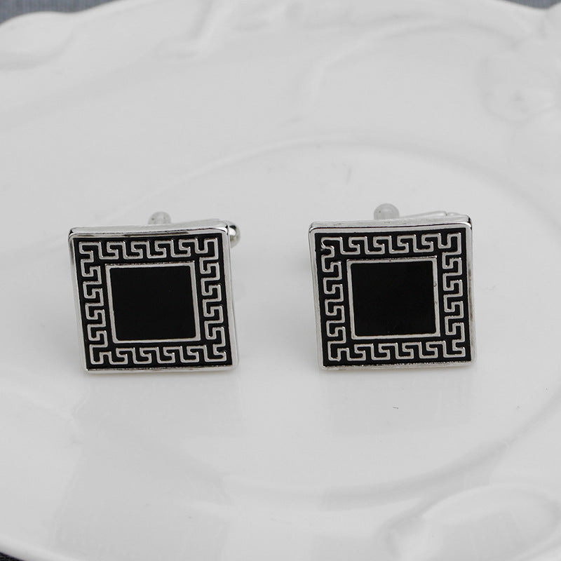 Pair of square cufflinks with black center and silver border on a white background