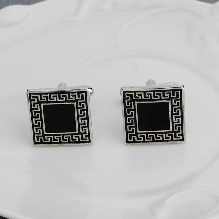 Pair of square cufflinks with black center and silver border on a white background
