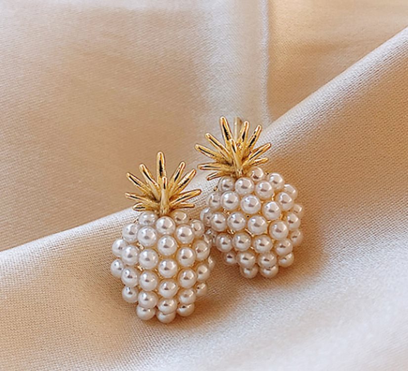 Pearl pineapple earrings on a beige fabric background