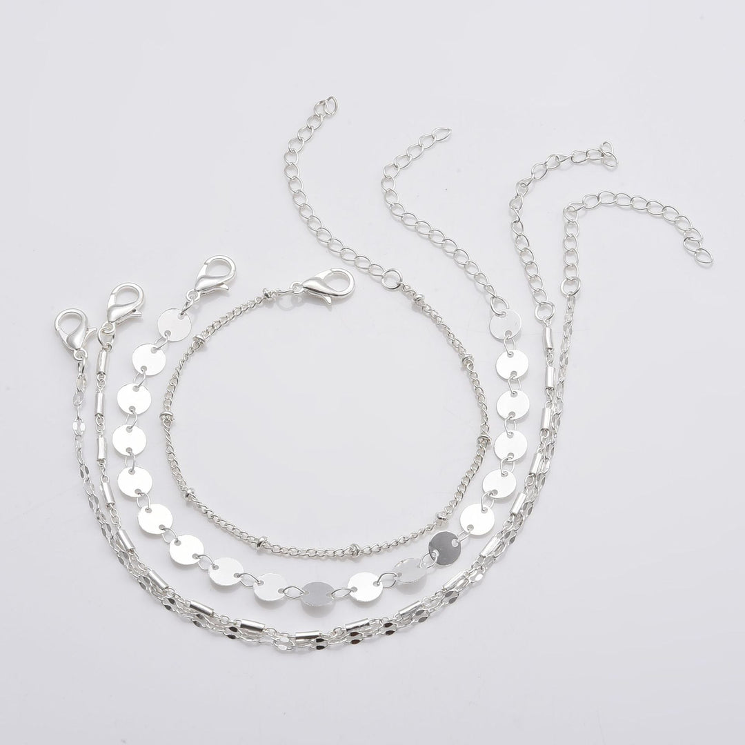 four Silver layered necklace on a light gray background